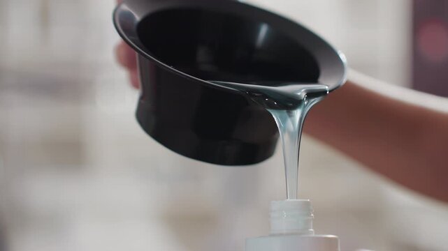 teal shampoo pouring into bottle, caucasian woman hand holds black funnel while viscous gel streams into clear dispenser, closeup texture and shine, soft bokeh salon background, product refill