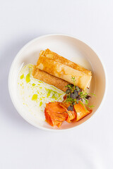 Plates of warm crepes accompanied by smoked salmon and vibrant green herbs create a delicious meal
