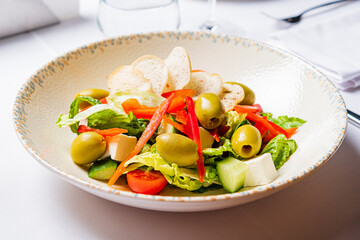 A vibrant garden salad with crisp greens, tomatoes, olives, and colorful peppers