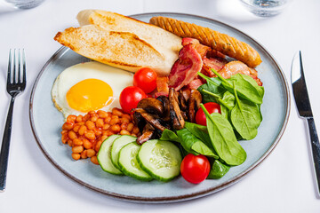 A beautiful breakfast spread includes eggs, crispy bacon, beans, and vibrant vegetables on a plate