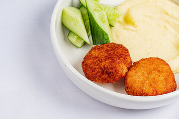 Savor crispy croquettes with creamy mashed potatoes and fresh cucumber