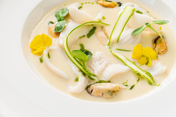A beautiful seafood creation featuring white fish, mussels, and garnishes in a rich, creamy sauce