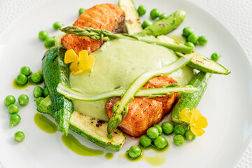 Tasty salmon fillets are beautifully arranged with vibrant vegetables and a creamy sauce