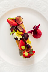 A charming dessert features vibrant fruits and delicate flowers on a creamy base, inviting taste