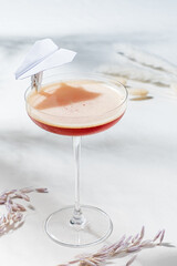 A colorful cocktail steals the show with its playful paper airplane garnish on a soft backdrop