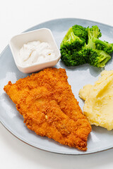 Vibrant plate holds golden fried fish, fresh broccoli, and smooth mashed potatoes with sauce