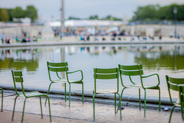 Bright green chairs invite visitors to relax by the peaceful pond in a bustling park