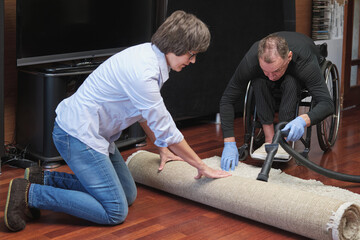 joint work of a man in a wheelchair and a woman cleaning their apartment