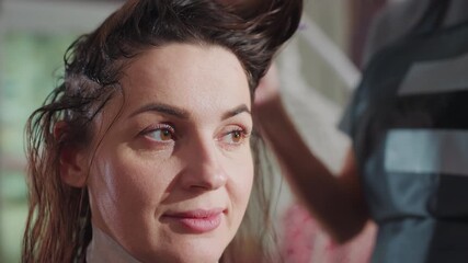 hair dye application, expert stylist paints vibrant hair color, skilled beautician delicately stains hair at salon, professional colorist attentively applies shade in inviting atmosphere