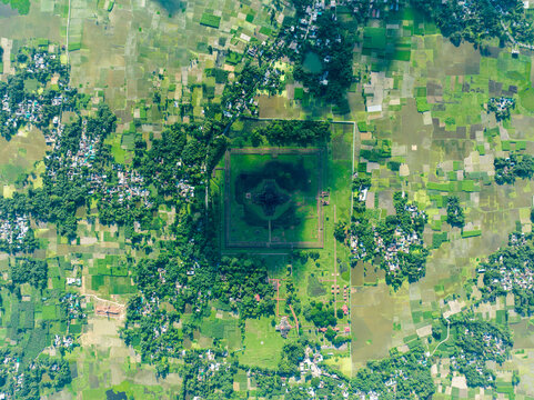 Aerial view of a large, ancient square structure surrounded by vibrant green fields and scattered settlements, Naogaon, Rajshahi Division, Bangladesh.