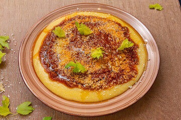 Hearty Italian polenta topped with rich ragù and grated cheese, styled on a rustic plate with fresh celery leaves for an authentic traditional comfort-food presentation