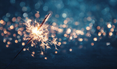 A sparkler burning brightly against a blurred background of bokeh lights glow