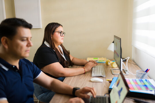 Couple working from home remotely on computers, focusing on online business and digital tasks in their office