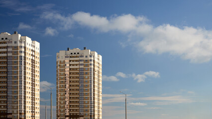 Urban residential architecture with multi storey apartment buildings and lampposts lighted with evening sun under blue sky with light clouds and copy space.
