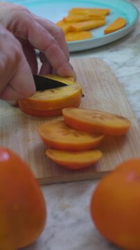vertical shot. A man cuts persimmons for a salad. Delicious persimmon salad. Healthy eating.