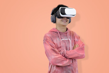 Excited young Asian man wear hoodie reacting with joy while wearing a virtual reality headset, symbolizing the thrilling first experience in studio background