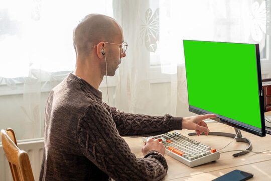 Programmer, young man working at computer with blank green screen, coding process, modern worker solving problems, specialist digital tasks, home office environment promoting productivity and calm - Powered by Adobe