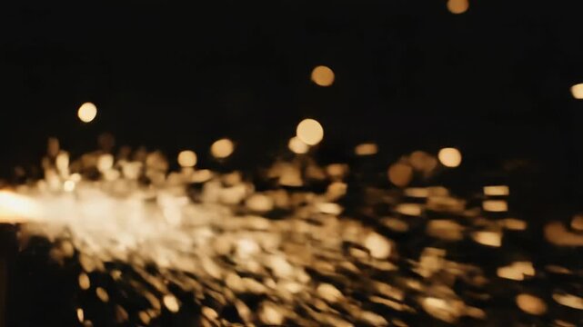 Abstract motion blur of bright golden sparks flying out from a source against a dark background with bokeh light effect