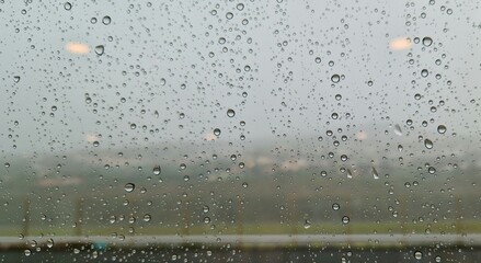 rain drops on the window View of a green village and a grey, dreary terrace