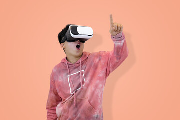 Excited young Asian man in a pink hoodie wearing a virtual reality headset, pointing upwards, symbolizing a discovery, great idea in studio background