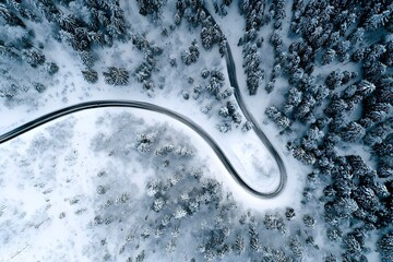 Aerial view of winding snowy forest road in serene winter landscape