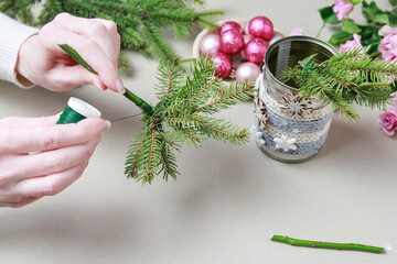 Florist at work: woman shows how to make modern Christmas decoration with fir, roses, pink baubles and decorative stars. The base is classic can. Step by step, complete tutorial.