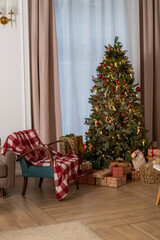Decorated Christmas tree and cozy armchair in a living room, ready for the holiday season.