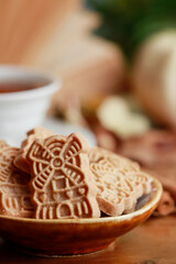 Bowl of speculaas biscuits and cup of tea in the background.
