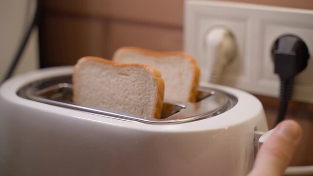 Two white slices of bread being put in a toaster, close-up