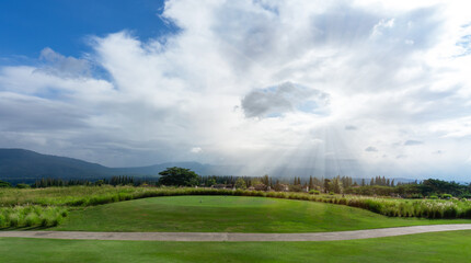 Landscape of green grass Lawn yard, golf couse with a concrete walkway on lawn land, mountain in background under cloudy sky