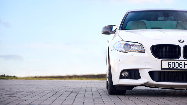 Minsk, Belarus - November, 1 2025: White BMW Car model 5 series F10 6-generation at parking under blue sky with copy space 16x9.