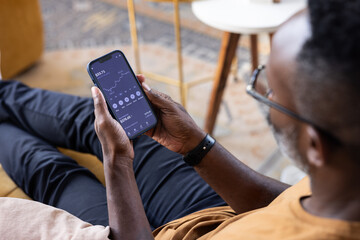 Man relaxing while checking financial data on phone