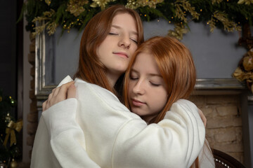 Two young women with long red hair wearing white Christmas sweaters