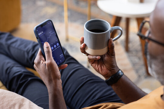 Over the shoulder view of man checking financial data with mobile banking app on a smartphone