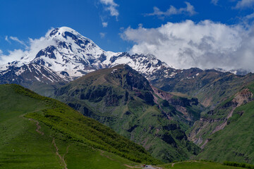 Obraz premium Mount Kazbek snowy peak above green Georgian hills