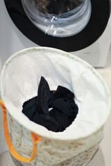 Laundry basket with black clothes next to washing machine in bathroom