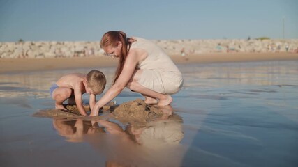 Mother and son playing with sand on the beach