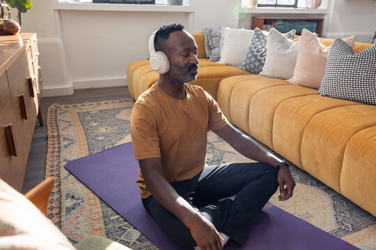 Man sits cross-legged meditating with headphones on