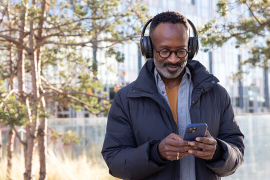 Man using smartphone while standing outdoors in a modern city development