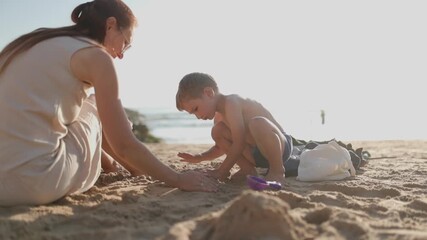 Mother and son building sandcastles together on the beach - Powered by Adobe