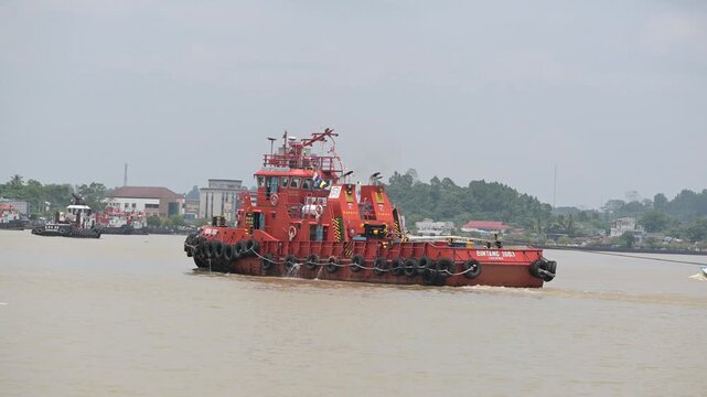 Berau - Indonesia, 25 August 2025 : tugboat pulling a coal-laden pontoon across the Segah River
