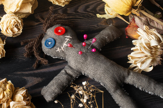 Mysterious voodoo doll with pins and dried flowers on dark background - Powered by Adobe