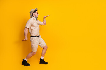 Adventurous safari man in beige shirt shorts and hat walking yellow background perfect for travel...