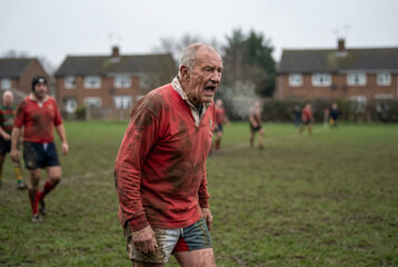 A determined rugby player shows effort and grit during a muddy match with friends