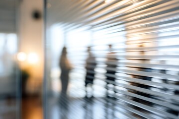 Obraz premium Blurred office figures seen through frosted glass and horizontal blinds.