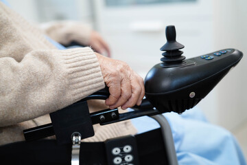 Asian elderly disability woman patient use joystick electric wheelchair in hospital.
