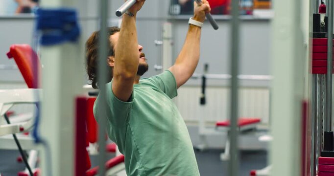Slow motion 4k footage of a Caucasian man working out in the gym. Workout for back muscles. Physical education as a norm of life for maintaining health.