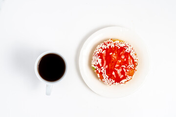 Overhead view of a round donut topped with glossy red strawberry jam and white sprinkles,...