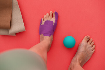 Woman foot with a kinesiology tape. Treatment for hallux valgus, sport pain. Top view.