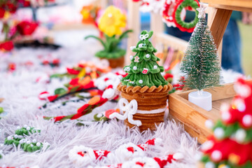 Cute handmade Christmas tree craft made from green pipe cleaners and beads displayed on a fluffy white surface. Festive DIY holiday decoration idea and creative art for sale at a local craft market